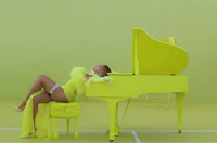 a woman in a yellow dress laying on top of a piano